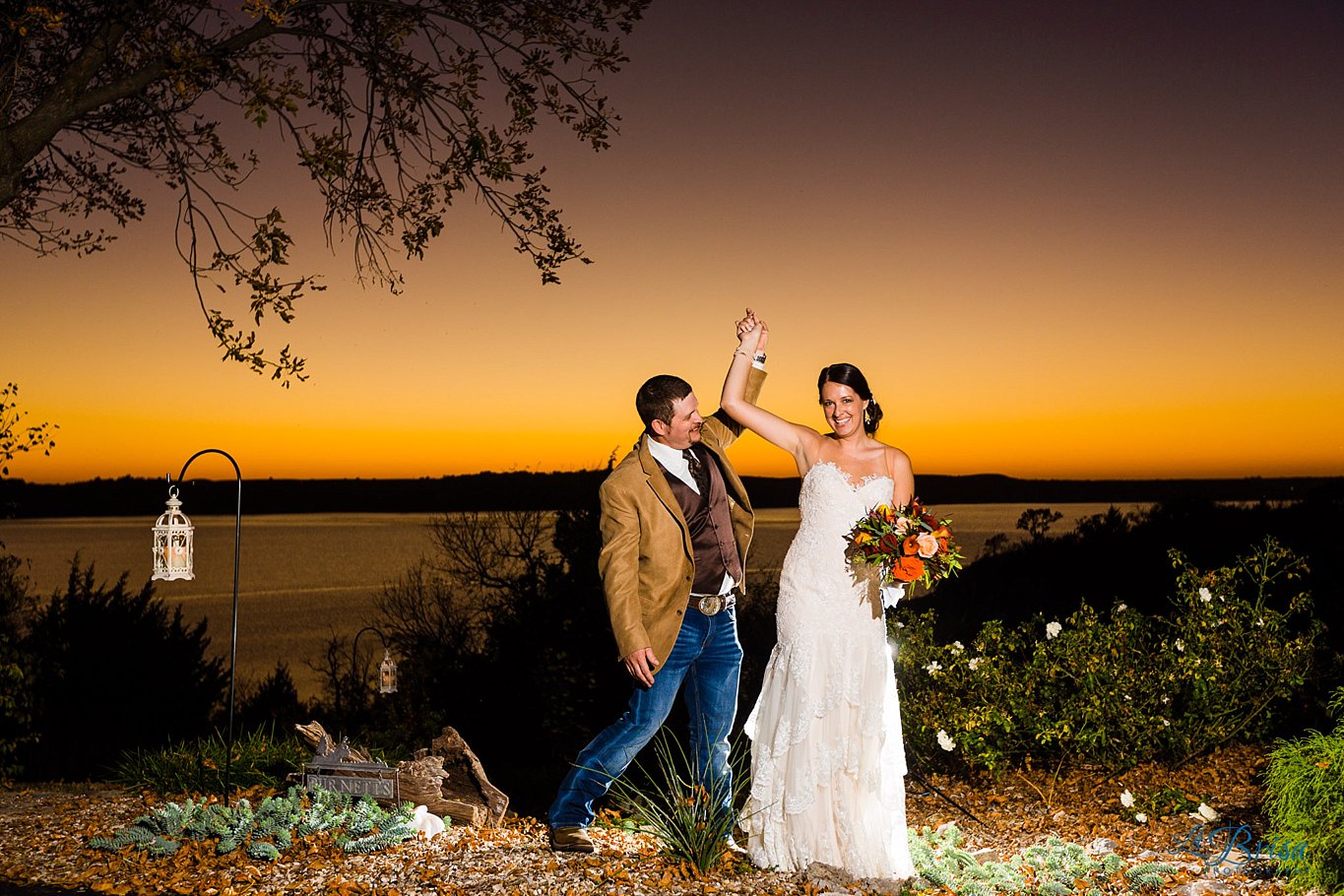 groom twirling bride overlooking lake at sunset
