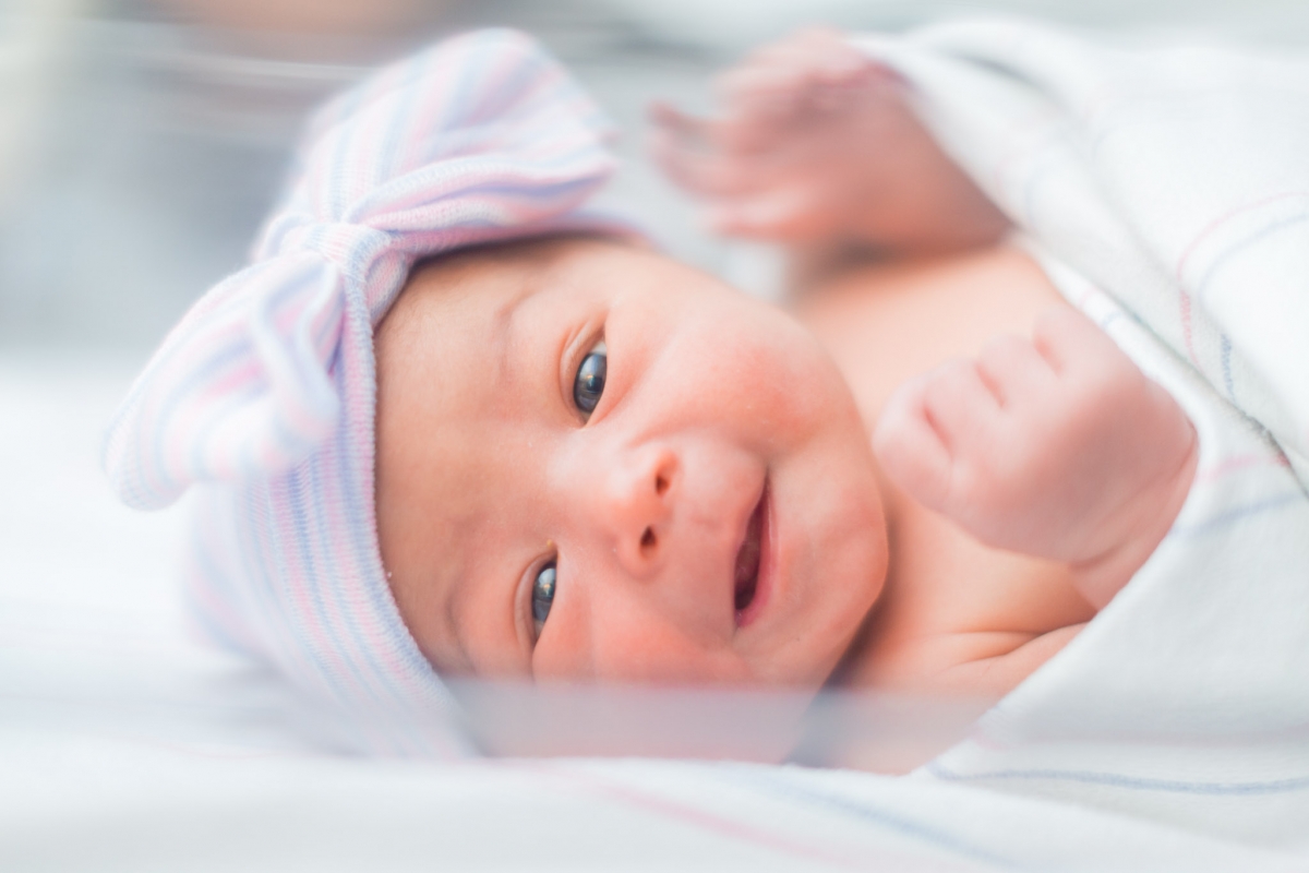 newborn Adalyn smiling in hospital crib